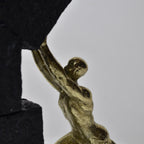 Vertical gold human struggle sculpture pulling textured sphere on stepped base