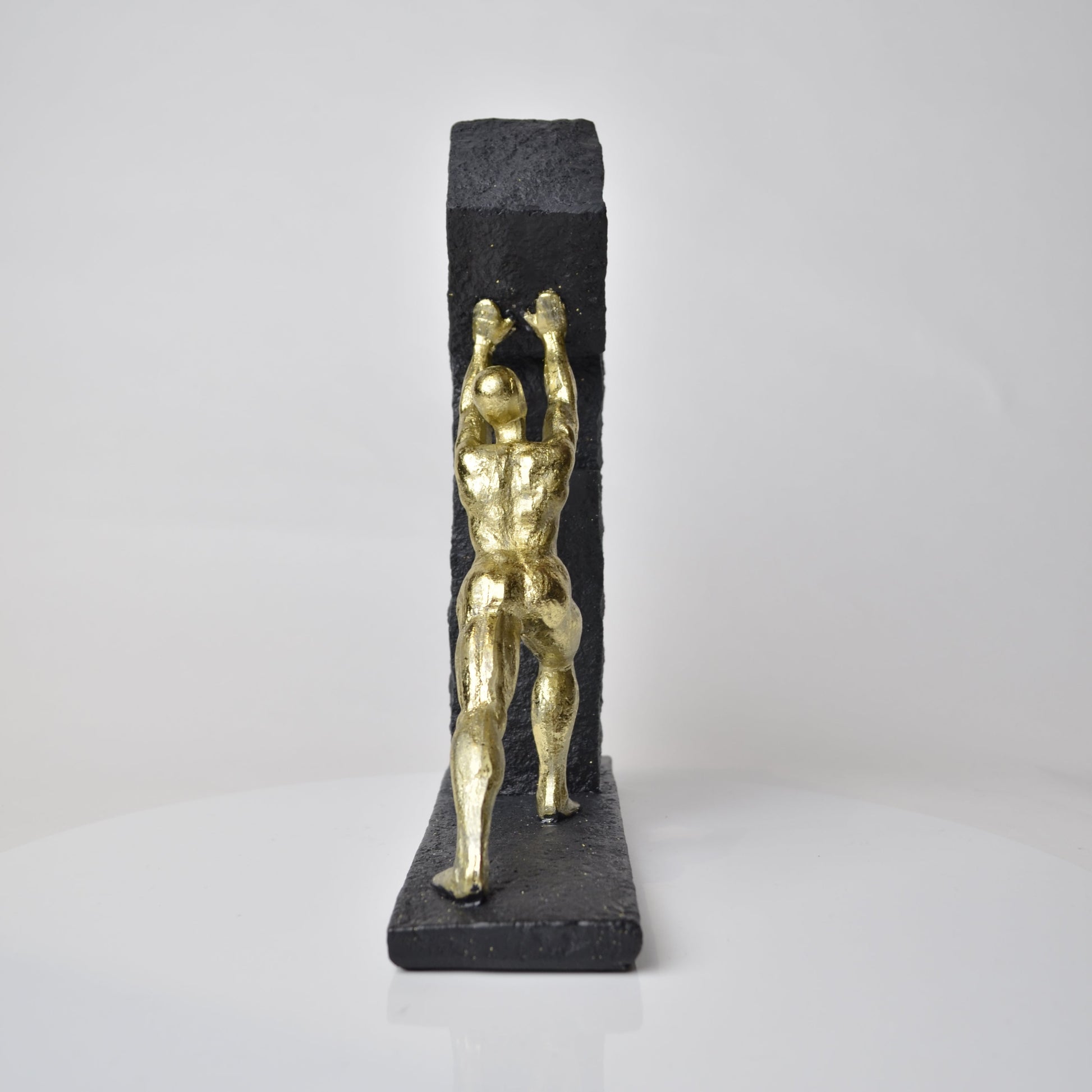 Vertical gold human struggle sculpture pulling textured sphere on stepped base
