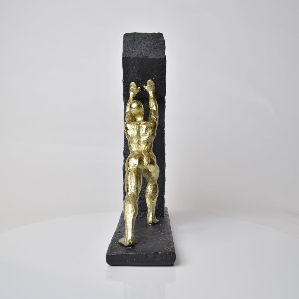 Vertical gold human struggle sculpture pulling textured sphere on stepped base