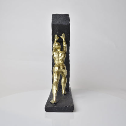 Vertical gold human struggle sculpture pulling textured sphere on stepped base
