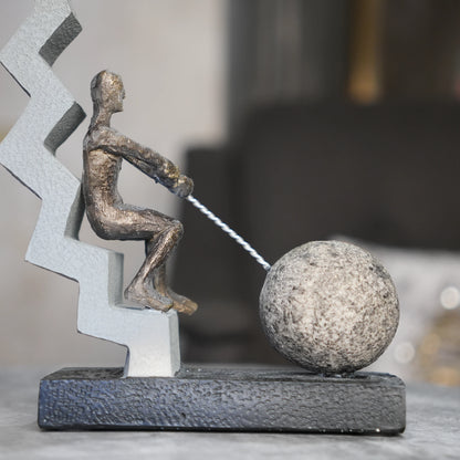 bronze figure pulling sphere on textured steps sculpture