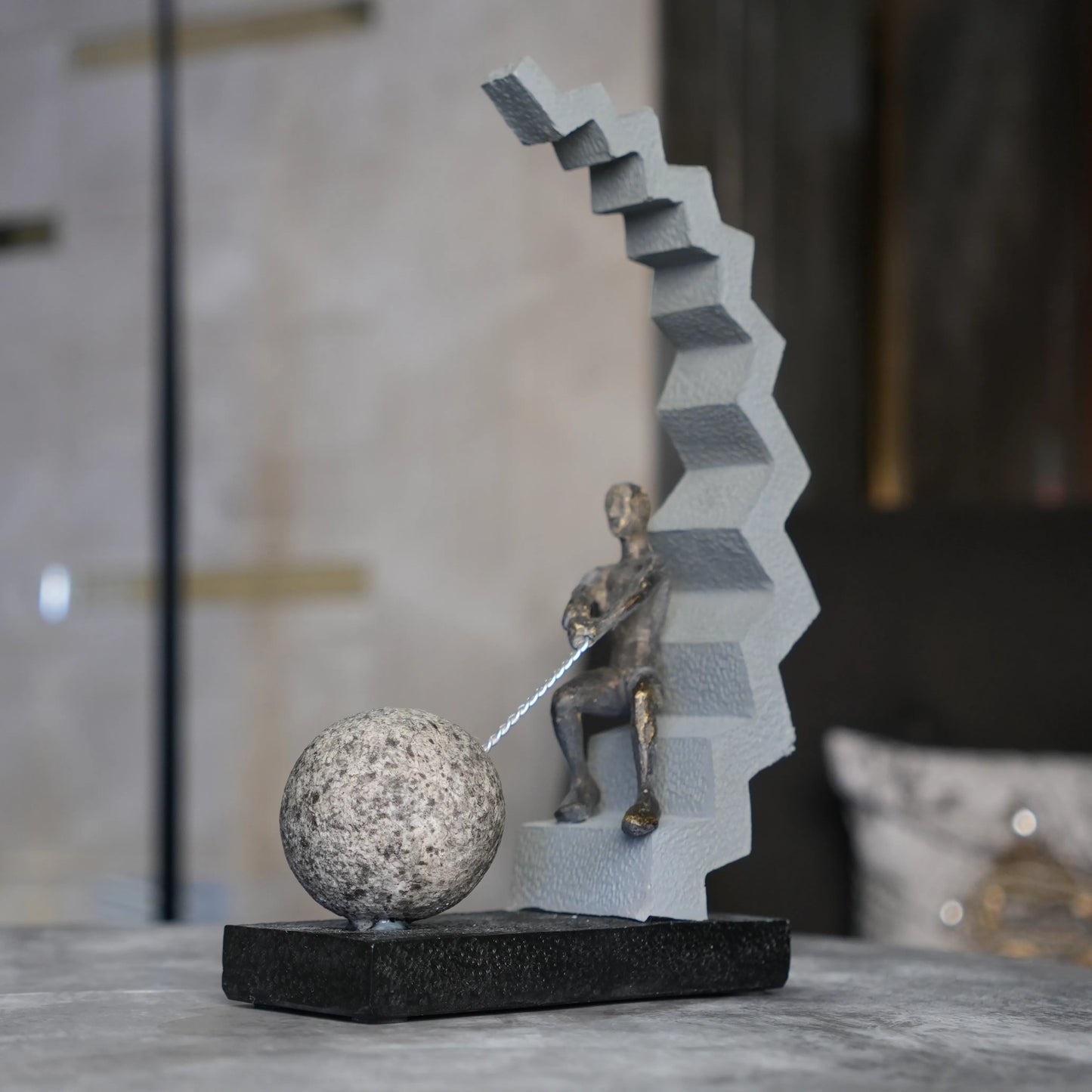 bronze figure pulling sphere on textured steps sculpture