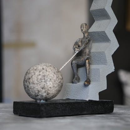 bronze figure pulling sphere on textured steps sculpture