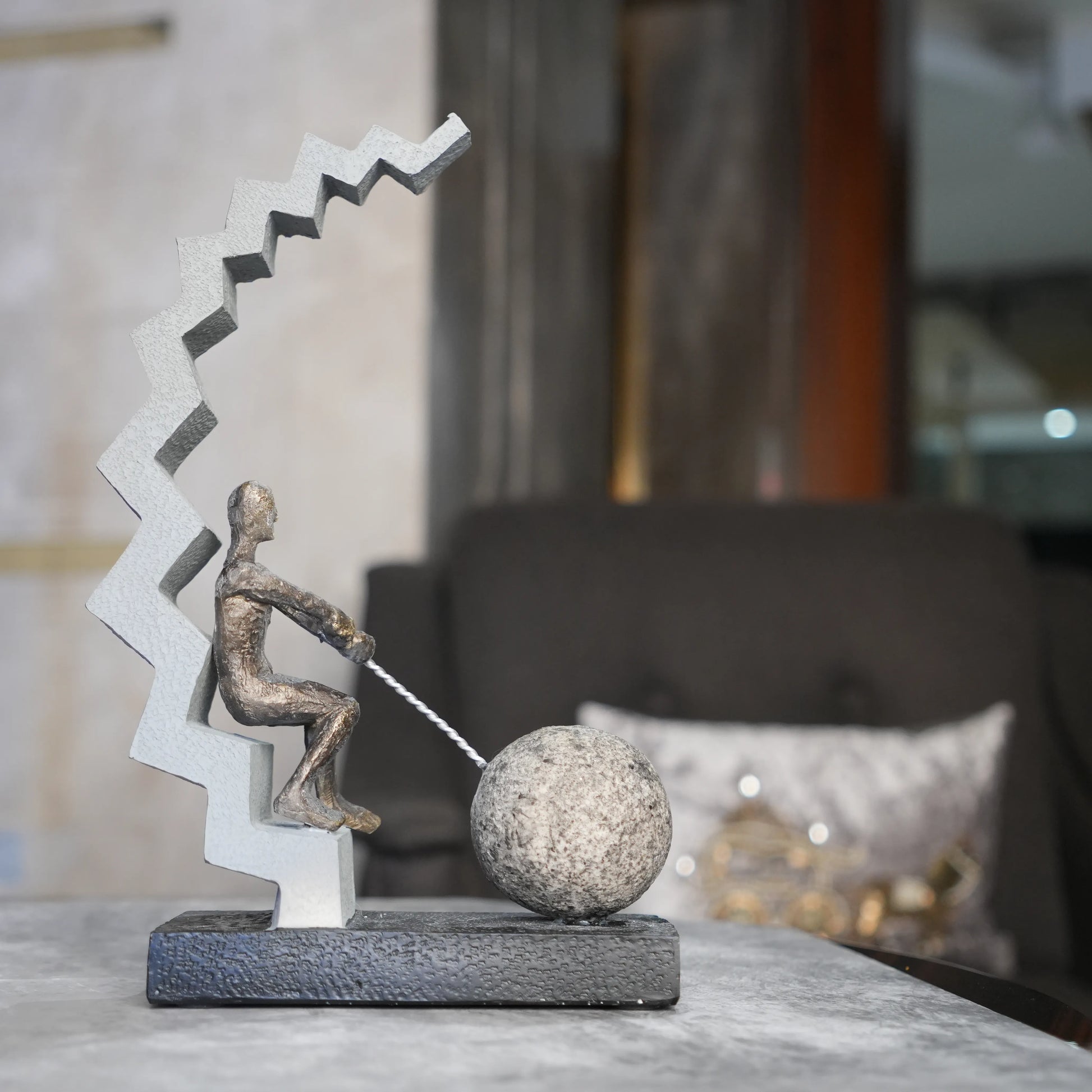 bronze figure pulling sphere on textured steps sculpture