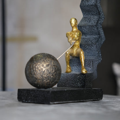 gold figure pulling sphere on textured steps sculpture