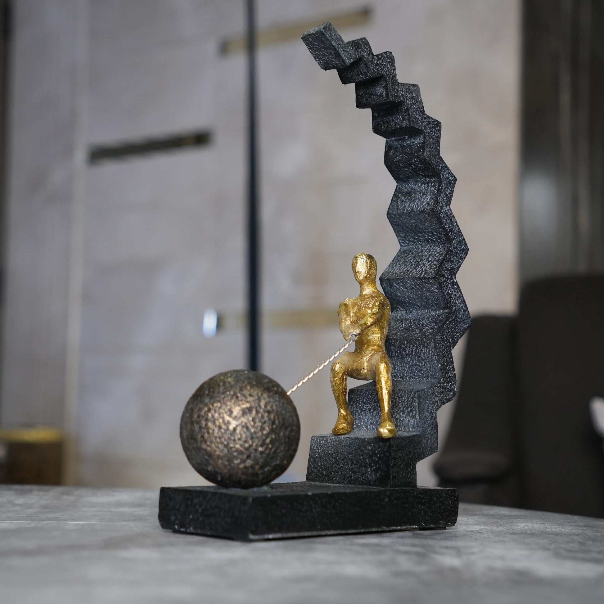 gold figure pulling sphere on textured steps sculpture