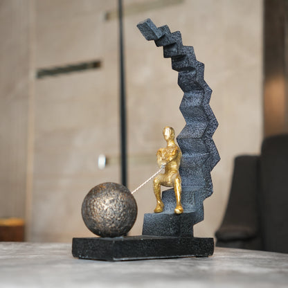gold figure pulling sphere on textured steps sculpture