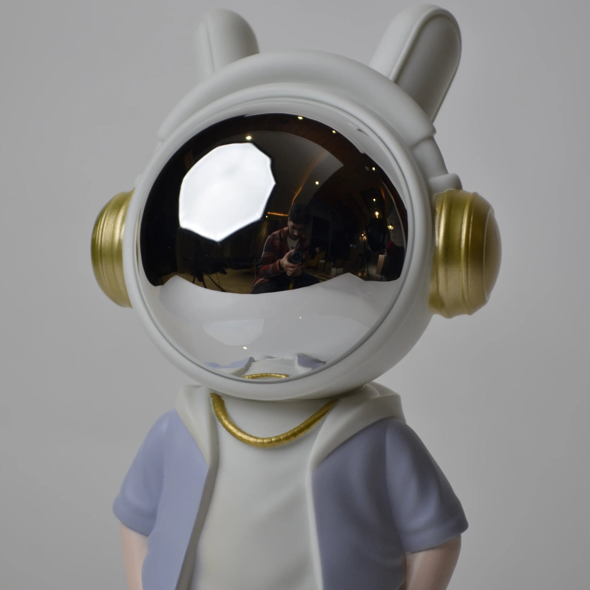 Astronaut figurine with chrome visor wearing blue shorts and lavender jacket.