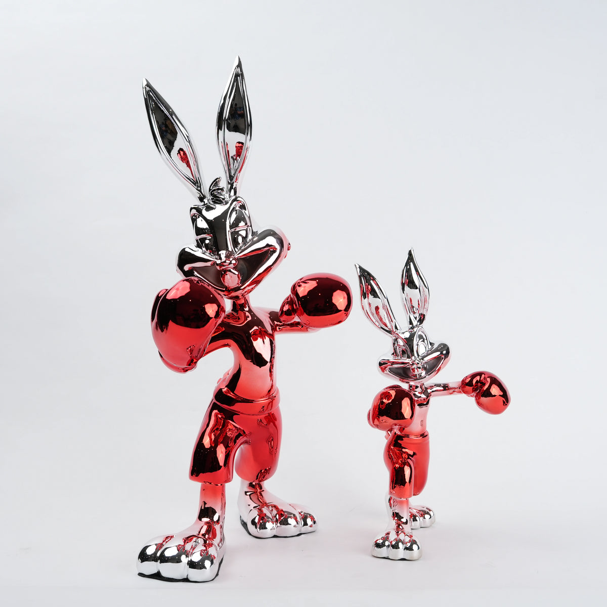 Two metallic red and silver rabbit figures on a white background