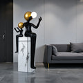 Black and gold human figurine duo holding a glowing orb on a marble pedestal sculpture