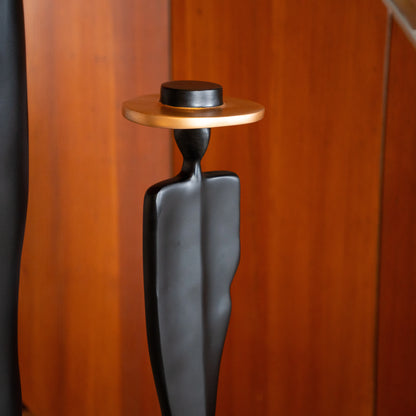 Tall matte black resin sculpture of three elongated human figures with bronze hats — Ethereal Harmony Sculpture by Ghar Art, handcrafted luxury decor symbolizing unity and balance.