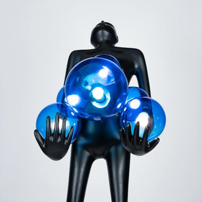 Tall matte black sculpture of human figure holding glowing blue light spheres — Azure Radiance Sculpture by Ghar Art, handcrafted illuminated modern home decor accent.