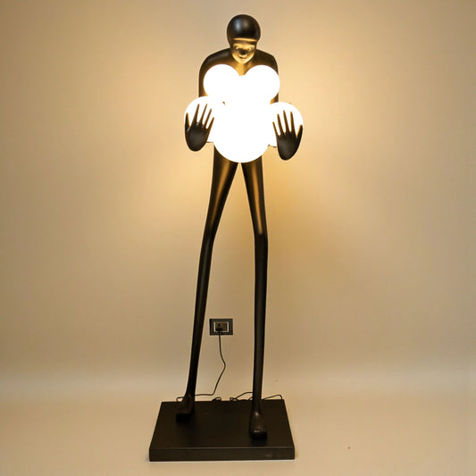 Tall matte black human sculpture holding glowing white orbs