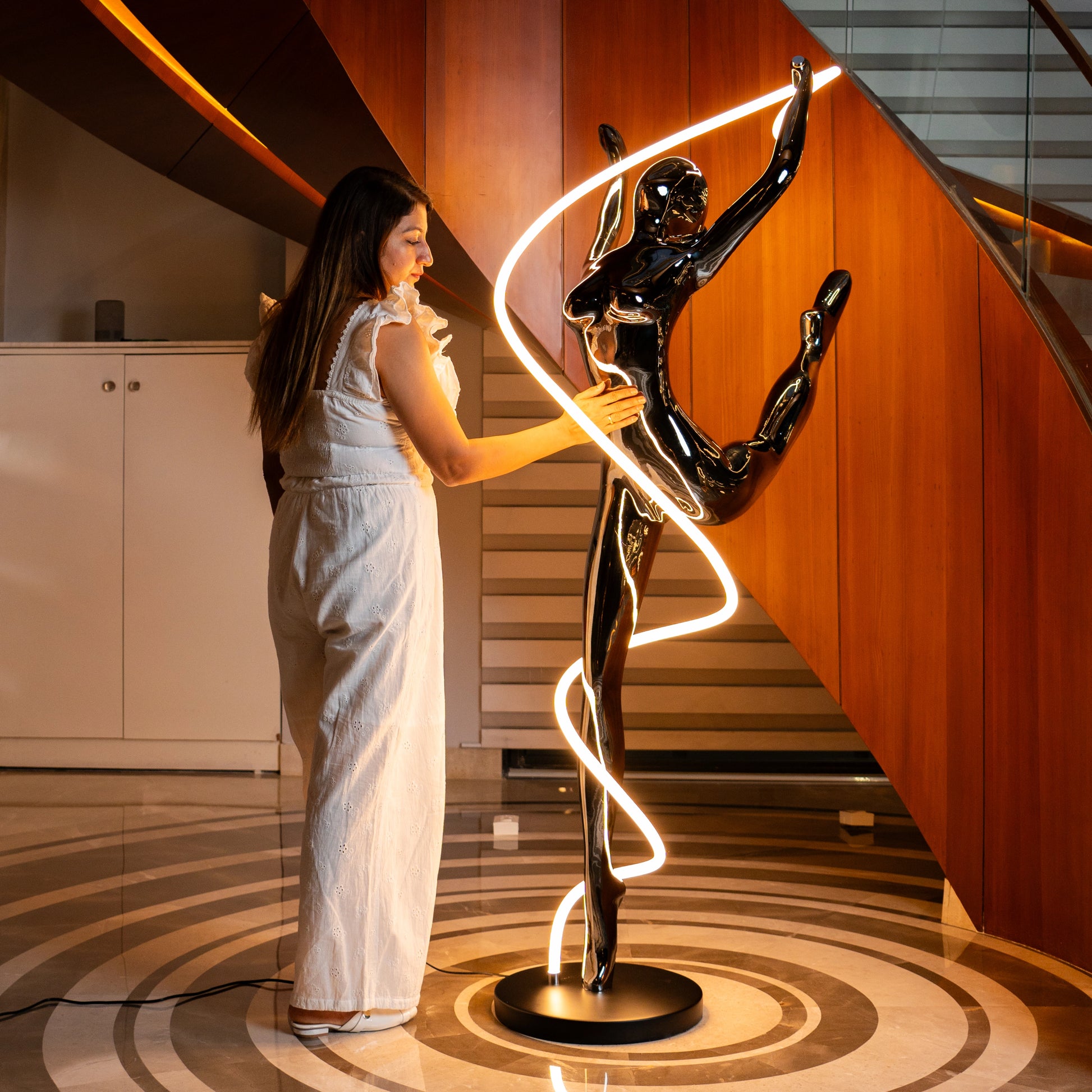 Metallic black human spiral floor sculpture with integrated LED light