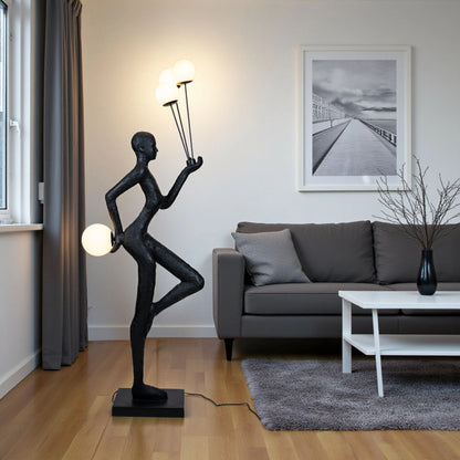 Matte black human-form sculpture holding illuminated orbs
