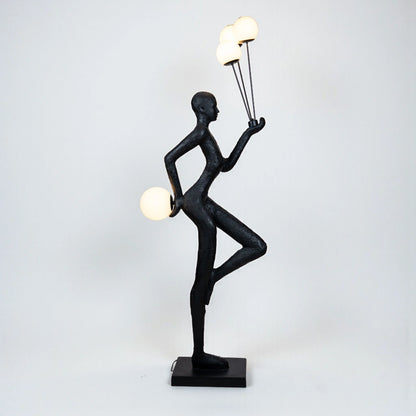 Matte black human-form sculpture holding illuminated orbs