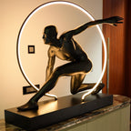 Matte black illuminated human motion sculpture with halo light ring on rectangular base