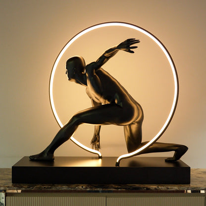 Matte black illuminated human motion sculpture with halo light ring on rectangular base