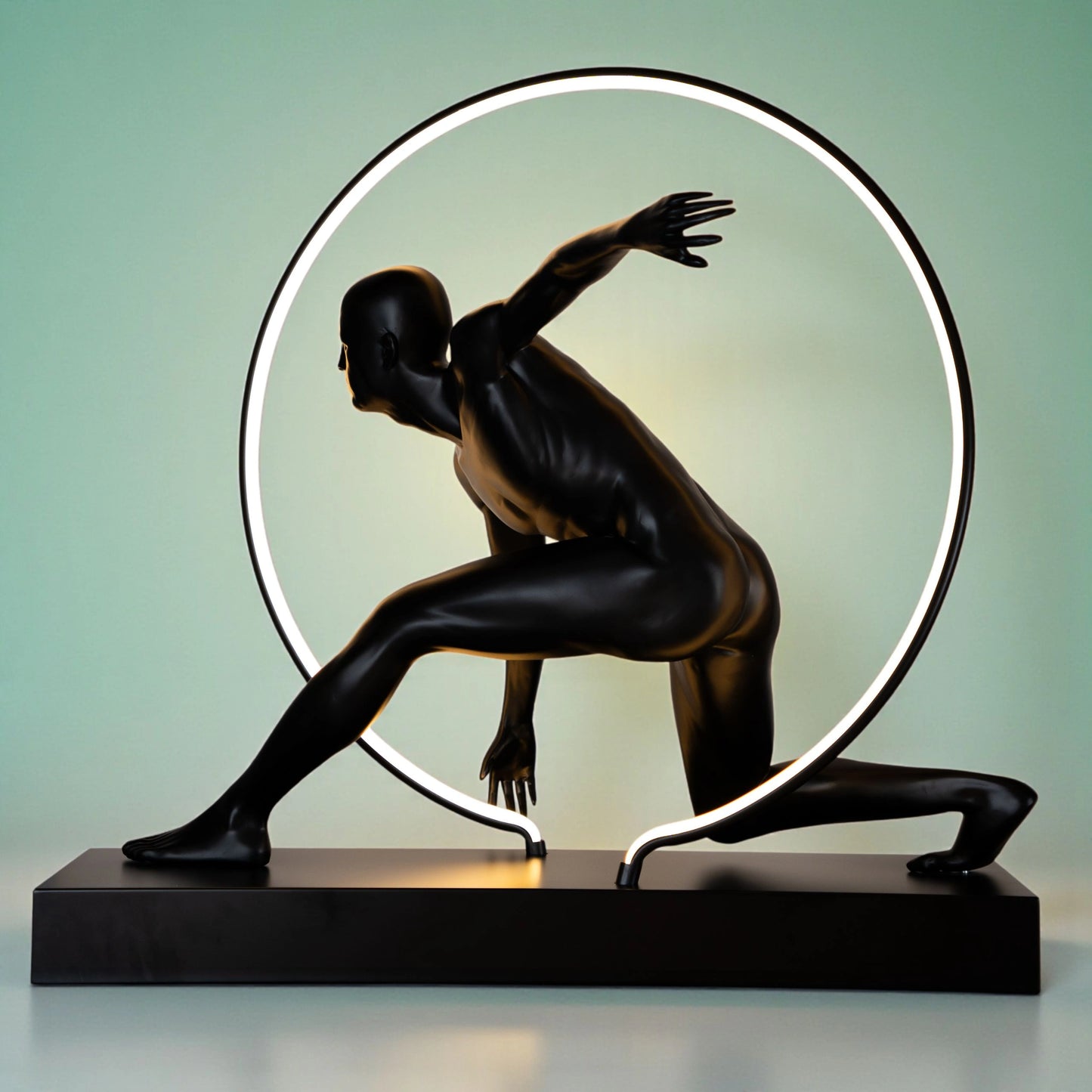 Matte black illuminated human motion sculpture with halo light ring on rectangular base