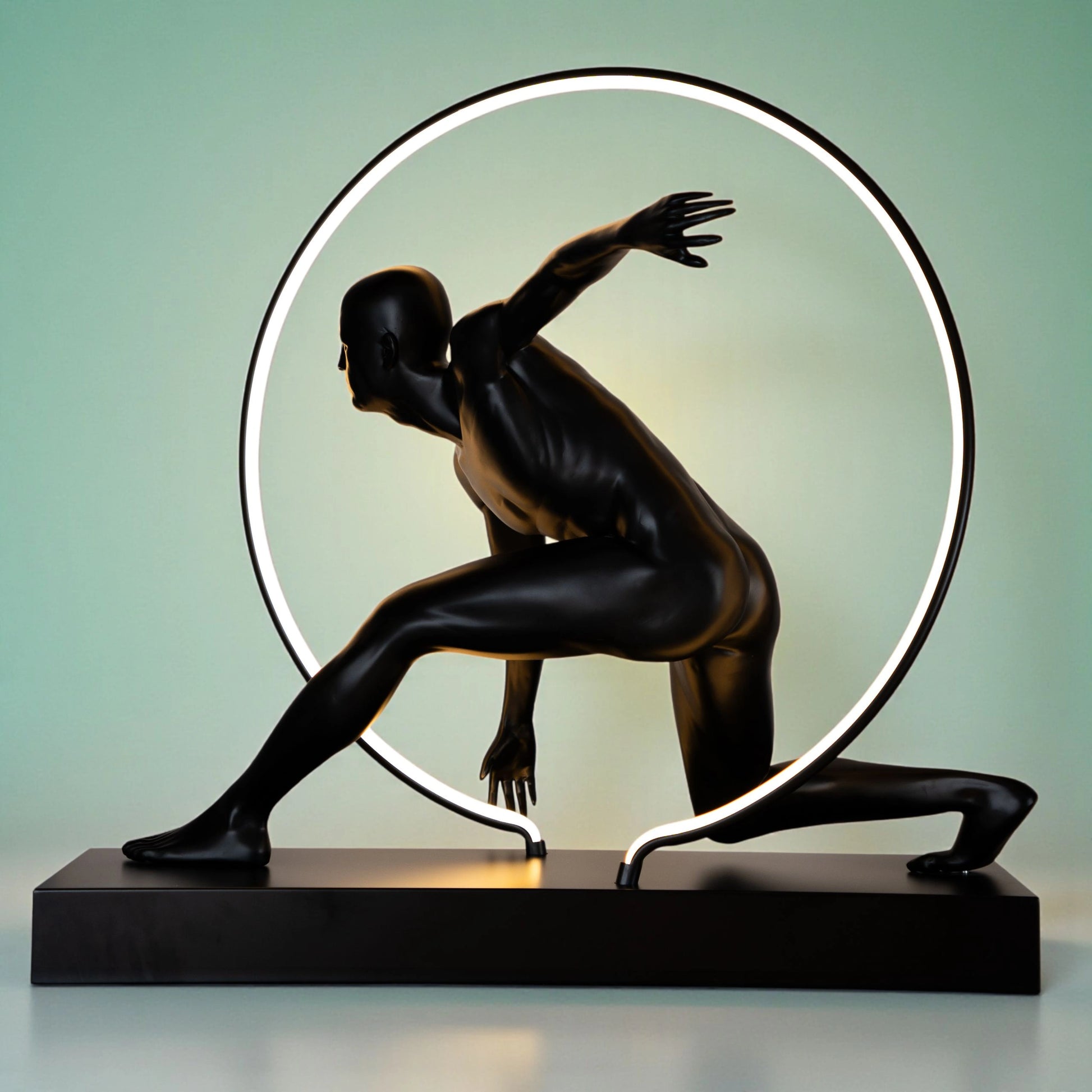 Matte black illuminated human motion sculpture with halo light ring on rectangular base