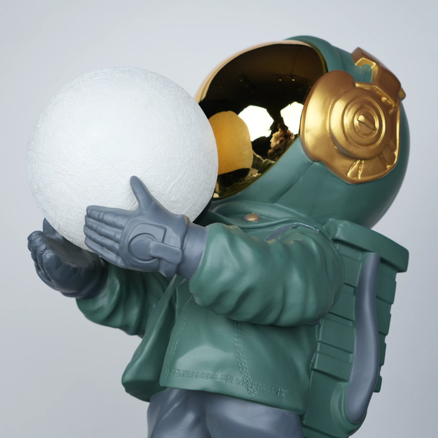 Green astronaut glow lamp holding illuminated sphere on white moon base.