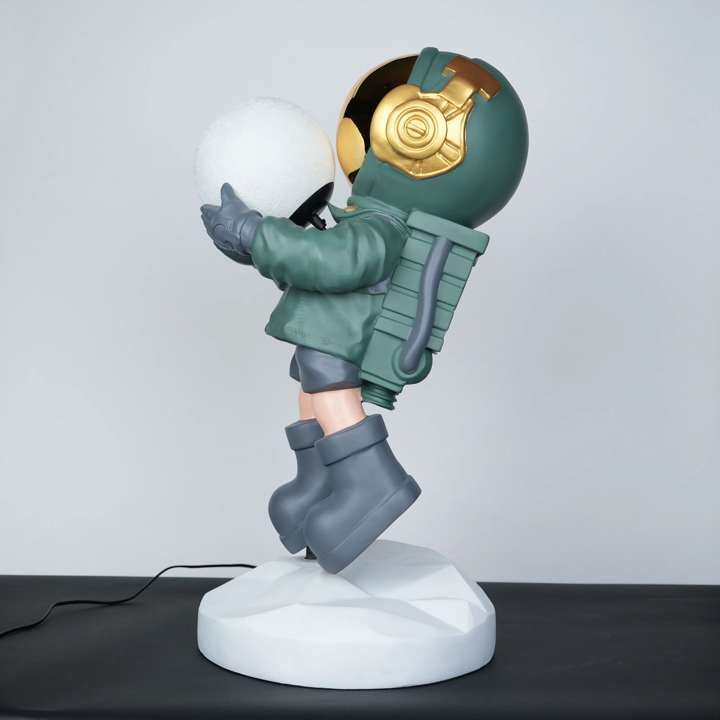Green astronaut glow lamp holding illuminated sphere on white moon base.