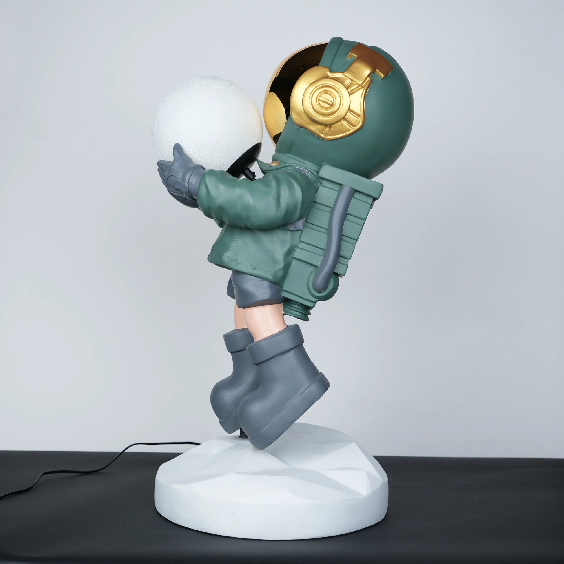 Green astronaut glow lamp holding illuminated sphere on white moon base.