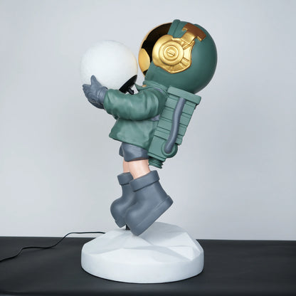 Green astronaut glow lamp holding illuminated sphere on white moon base.