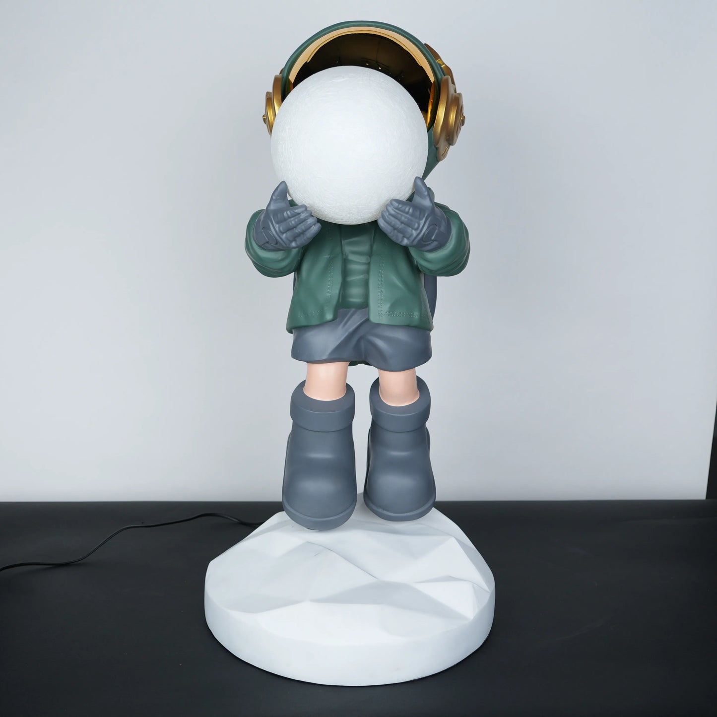 Green astronaut glow lamp holding illuminated sphere on white moon base.