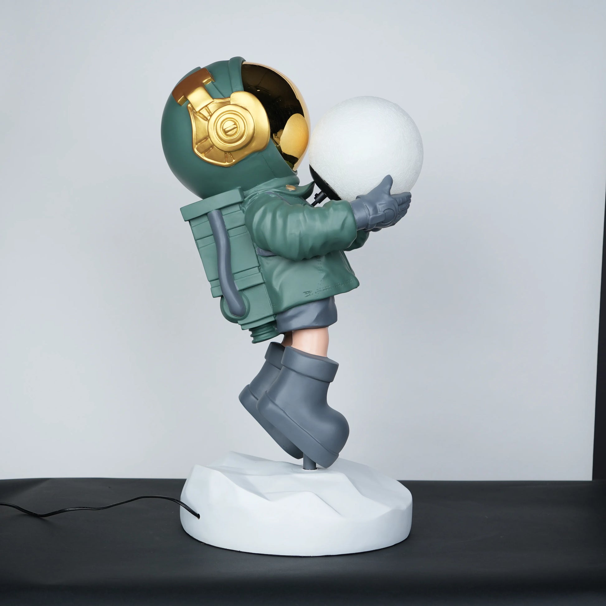 Green astronaut glow lamp holding illuminated sphere on white moon base.