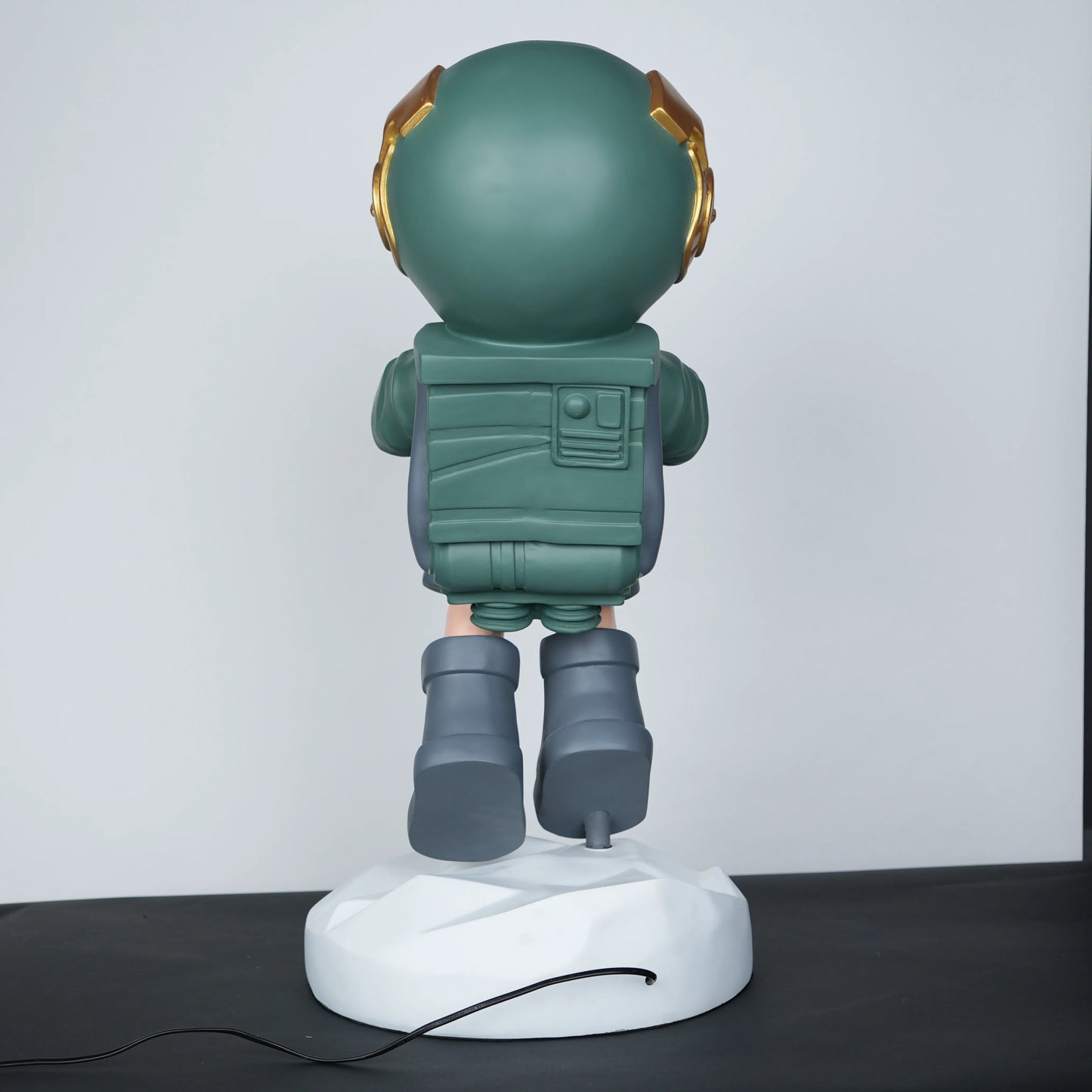 Green astronaut glow lamp holding illuminated sphere on white moon base.