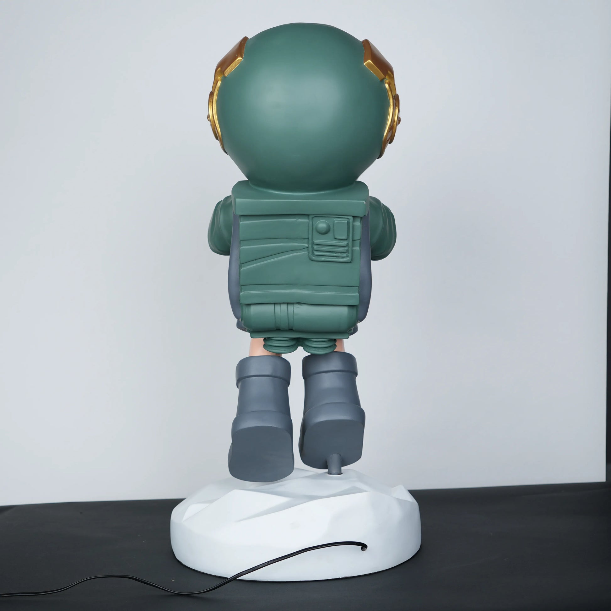 Green astronaut glow lamp holding illuminated sphere on white moon base.