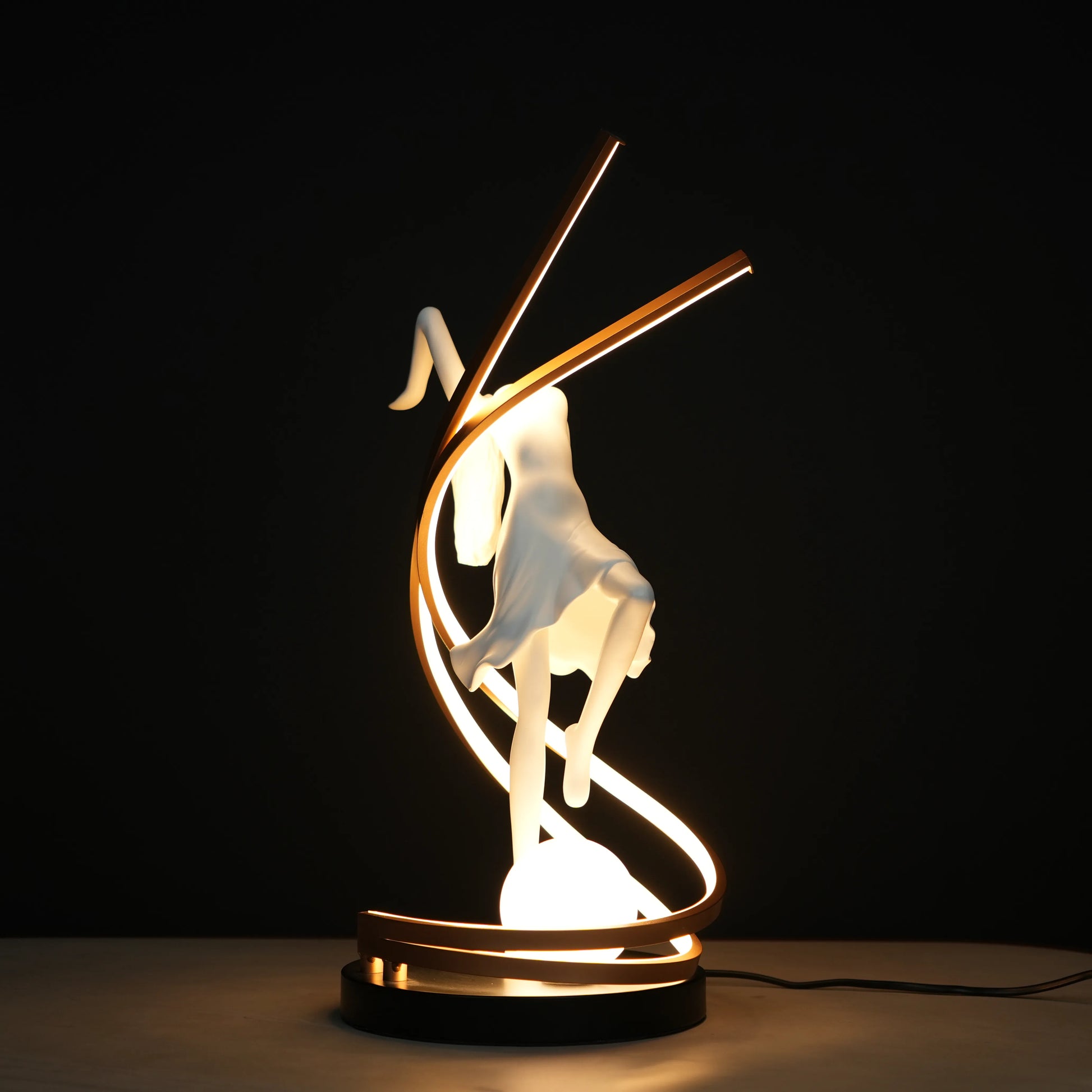 Small white sculpture lamp of a dancing woman with sweeping LED arcs and a glowing orb on a black base.