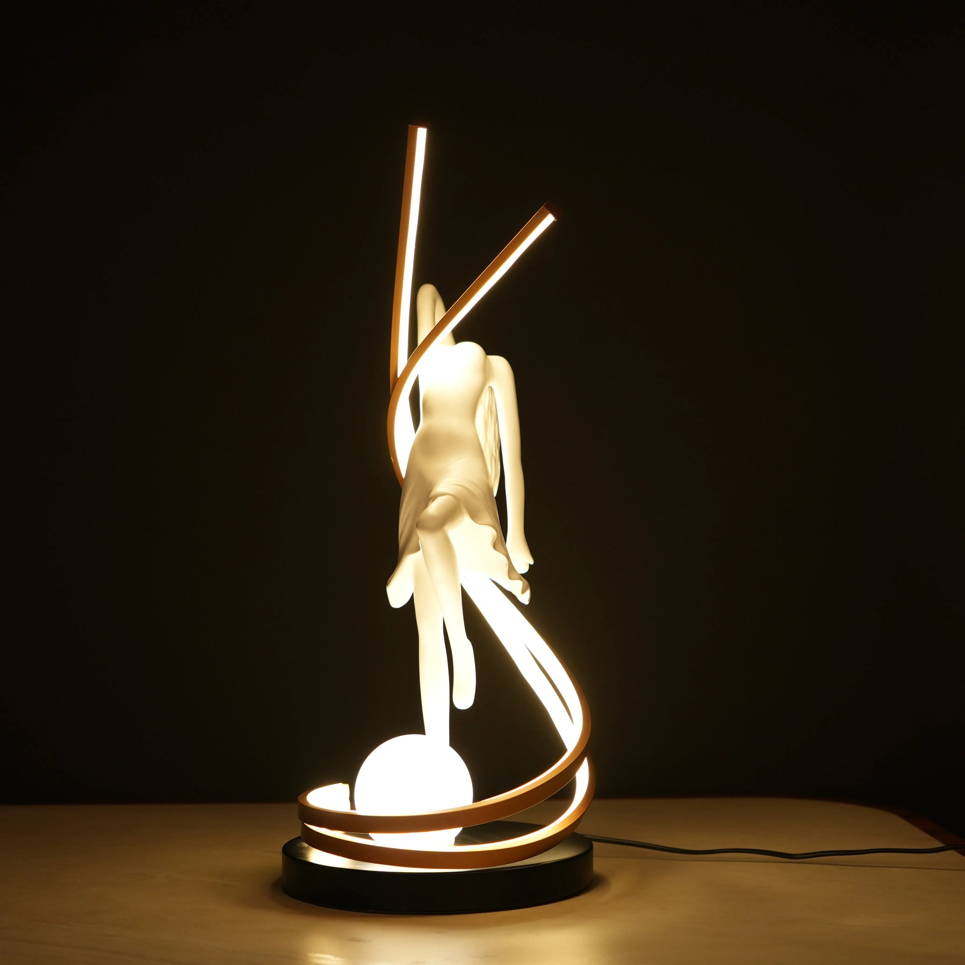 Small white sculpture lamp of a dancing woman with sweeping LED arcs and a glowing orb on a black base.