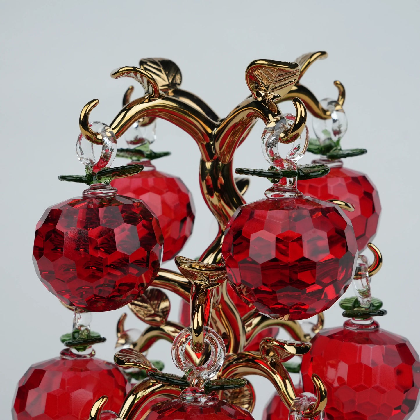 Dense cluster golden crystal apple tree with multiple red faceted apples on a mirrored base.