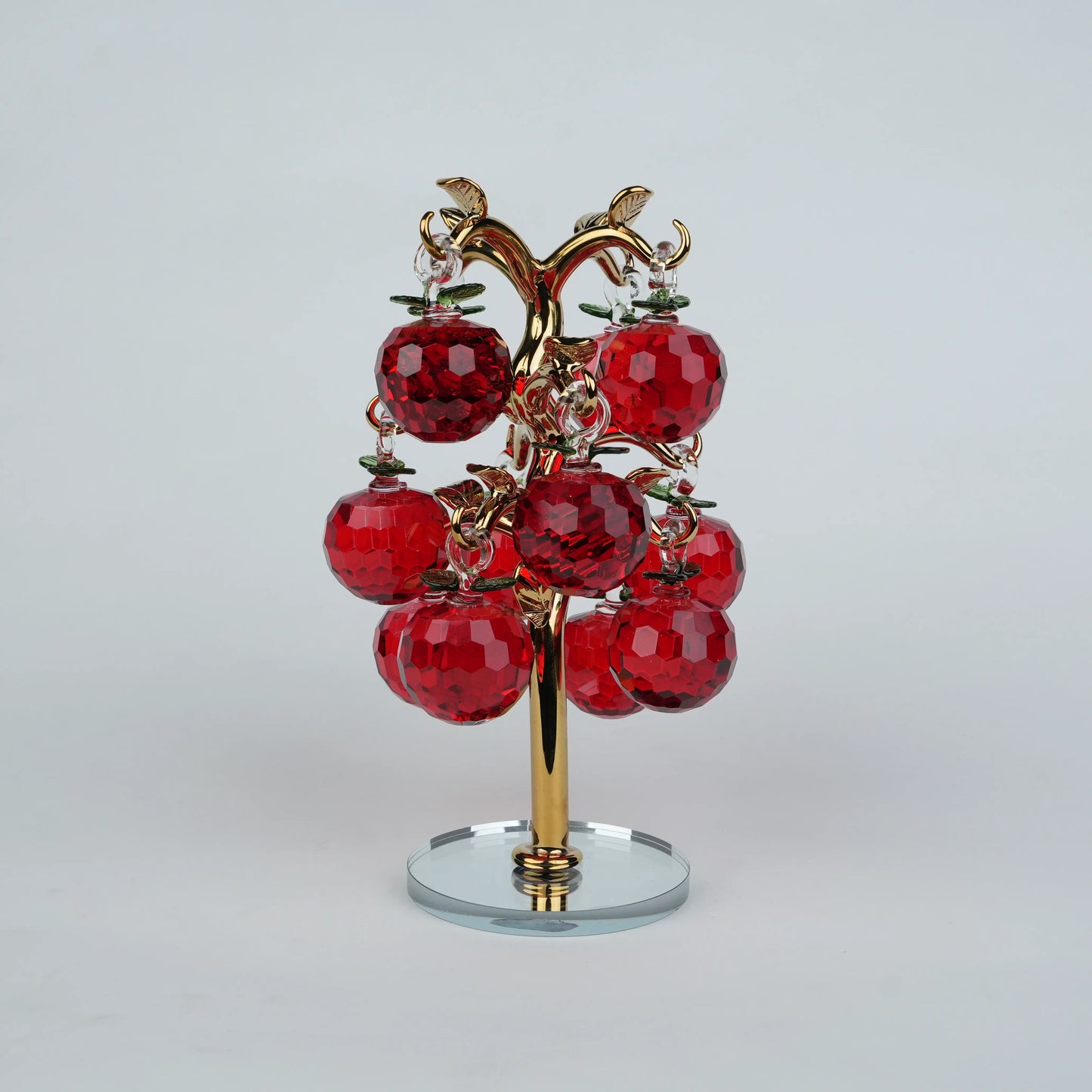 Dense cluster golden crystal apple tree with multiple red faceted apples on a mirrored base.