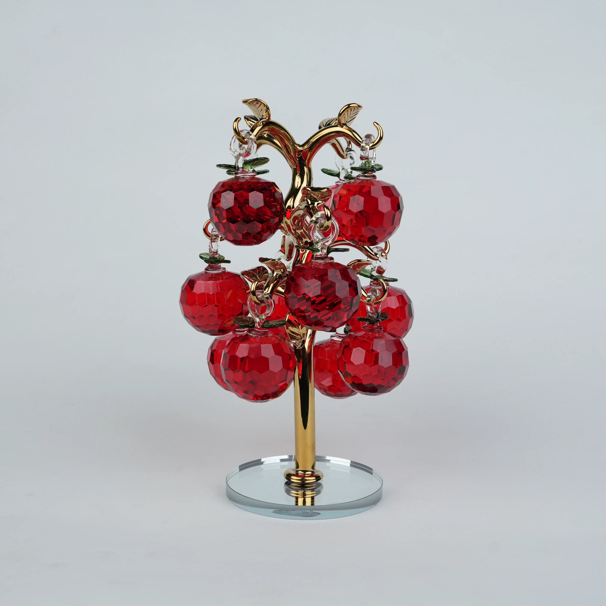 Dense cluster golden crystal apple tree with multiple red faceted apples on a mirrored base.