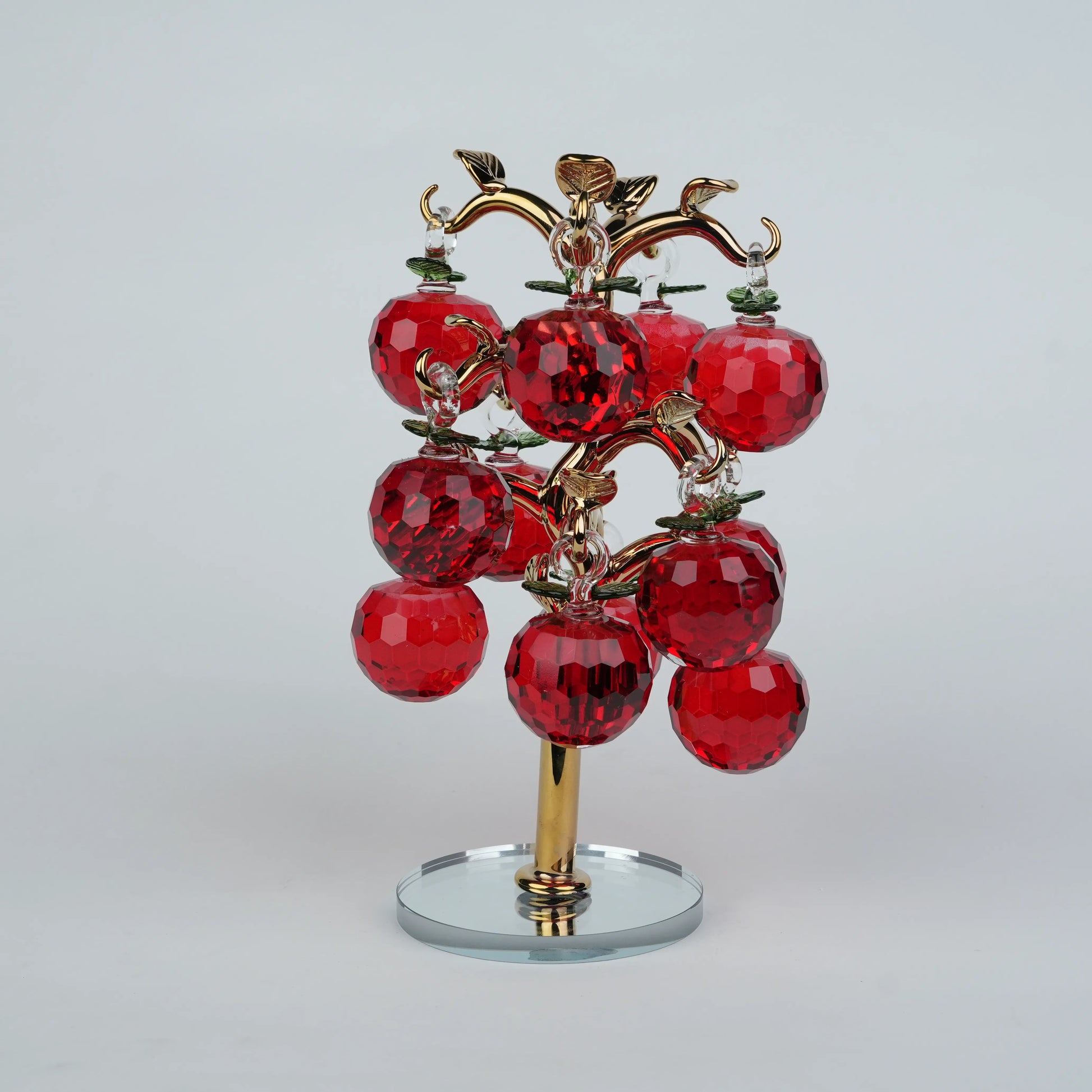 Dense cluster golden crystal apple tree with multiple red faceted apples on a mirrored base.