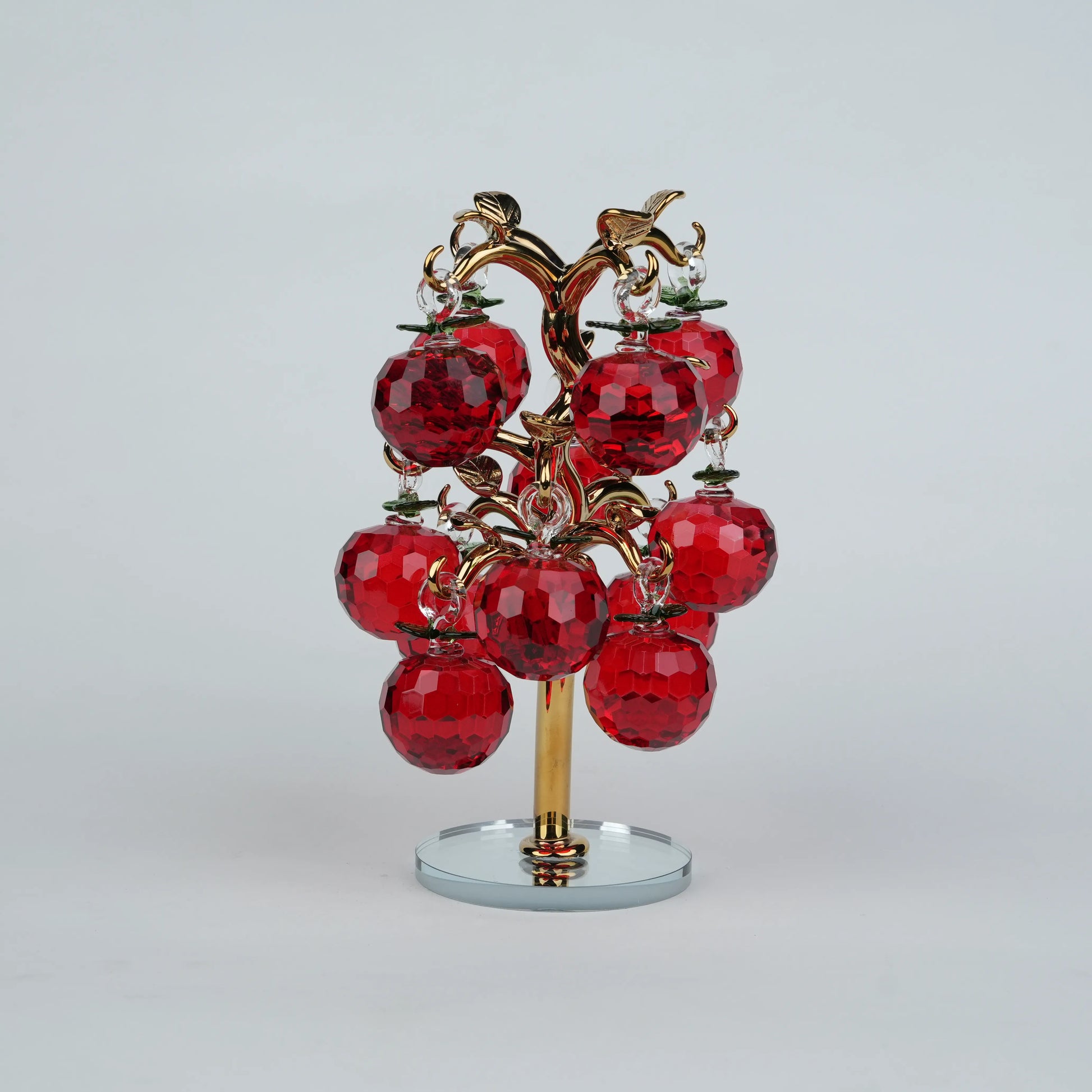 Dense cluster golden crystal apple tree with multiple red faceted apples on a mirrored base.