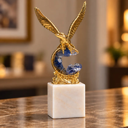 Golden eagle rising from blue crystal wave sculpture on white marble base