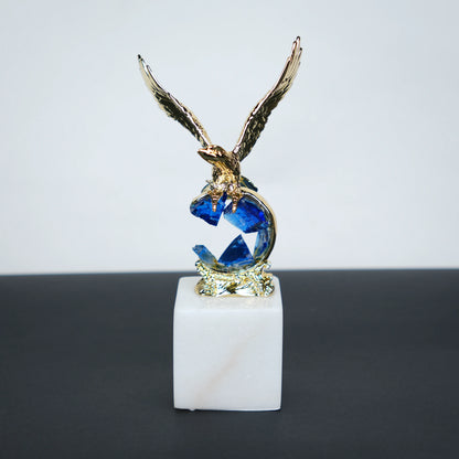 Golden eagle rising from blue crystal wave sculpture on white marble base