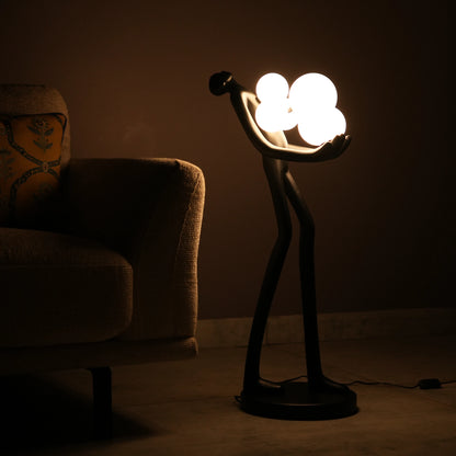Black abstract human sculpture floor lamp holding glowing cloud-shaped warm white globes