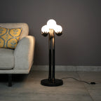 Luxury sculptural floor lamp with abstract human figure holding glowing orb lights in modern artistic black finish