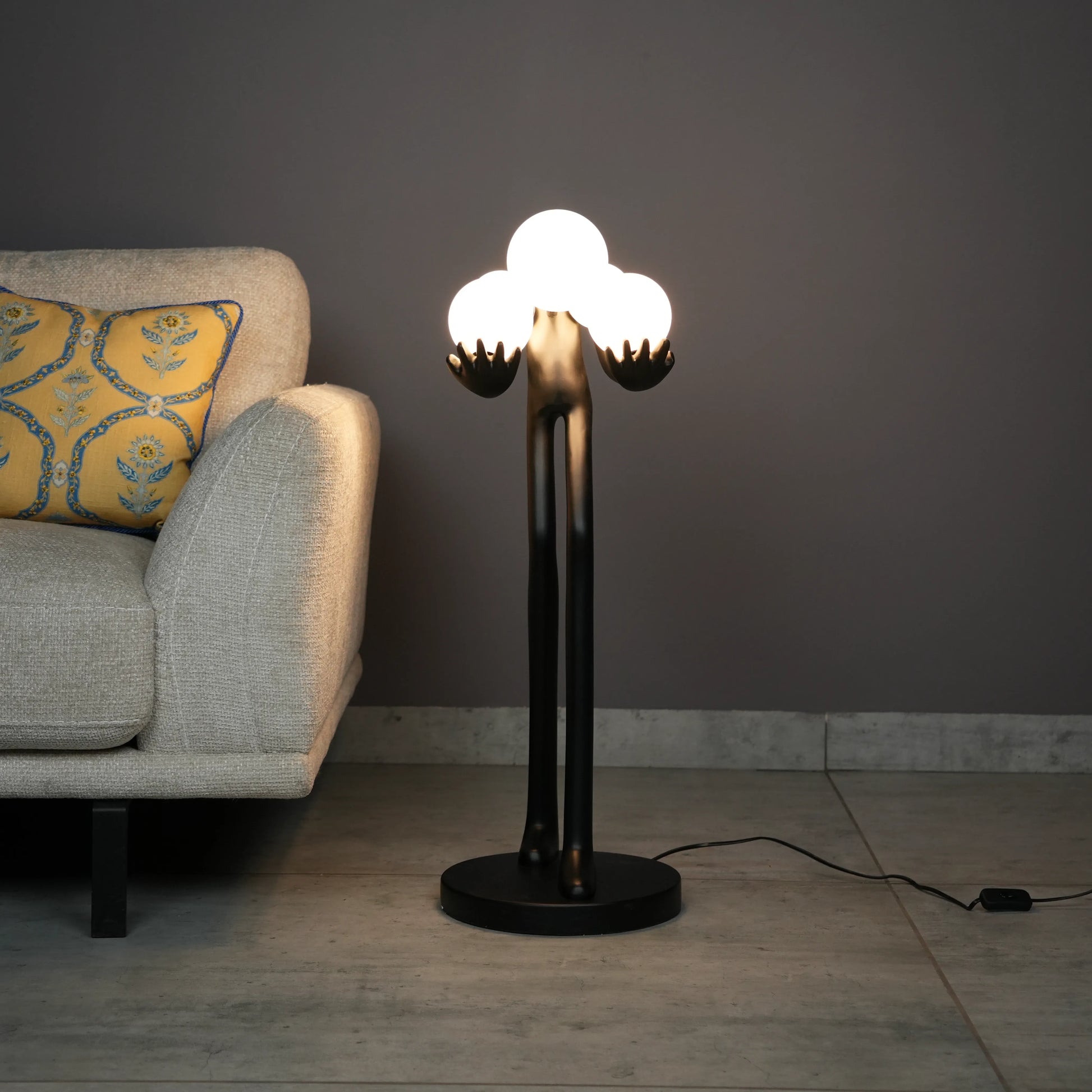 Black abstract human sculpture floor lamp holding glowing cloud-shaped warm white globes