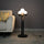 Luxury sculptural floor lamp with abstract human figure holding glowing orb lights in modern artistic black finish