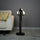 Black abstract human sculpture floor lamp holding glowing cloud-shaped warm white globes