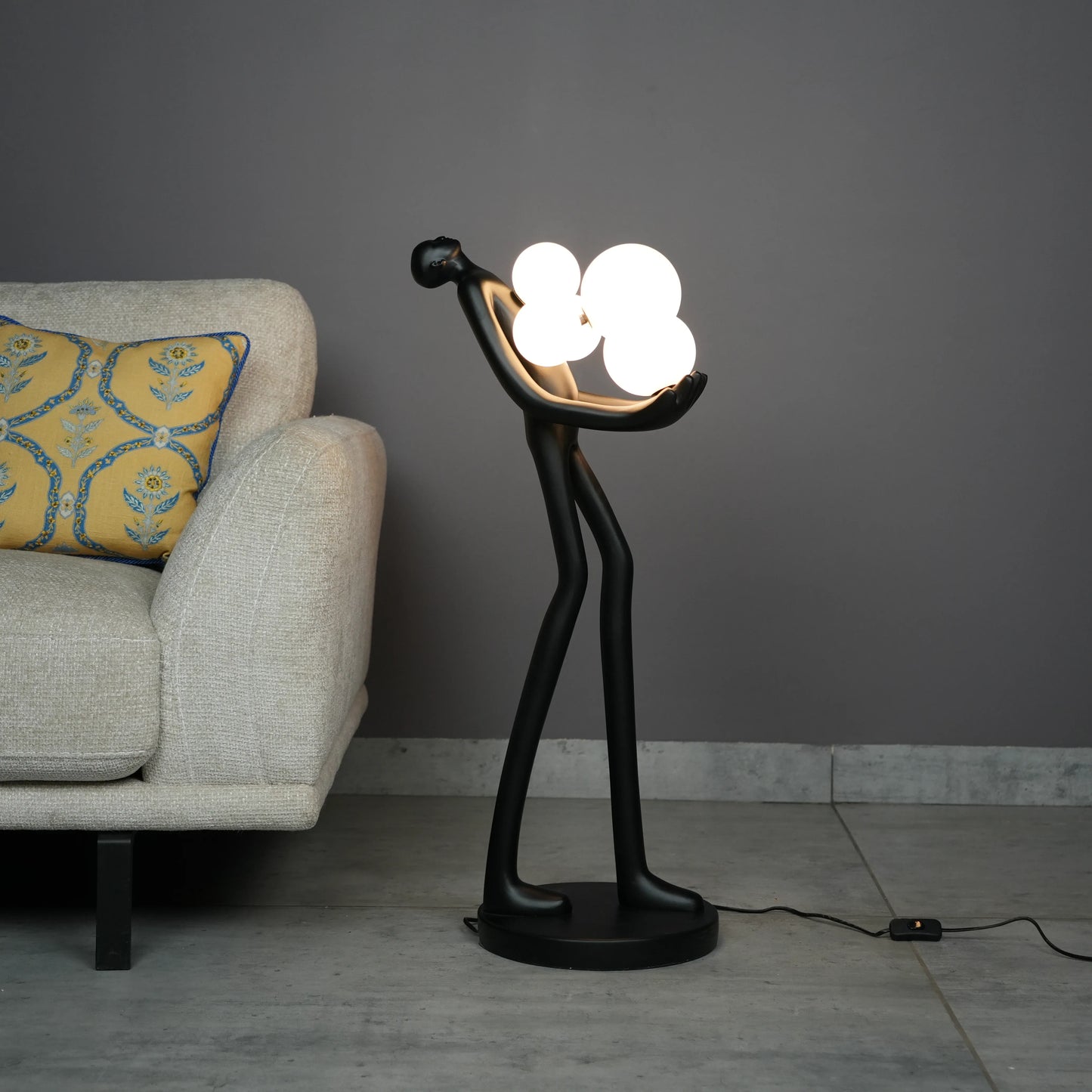 Black abstract human sculpture floor lamp holding glowing cloud-shaped warm white globes