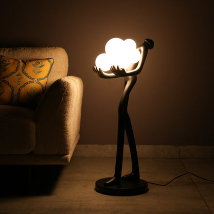 Black abstract human sculpture floor lamp holding glowing cloud-shaped warm white globes