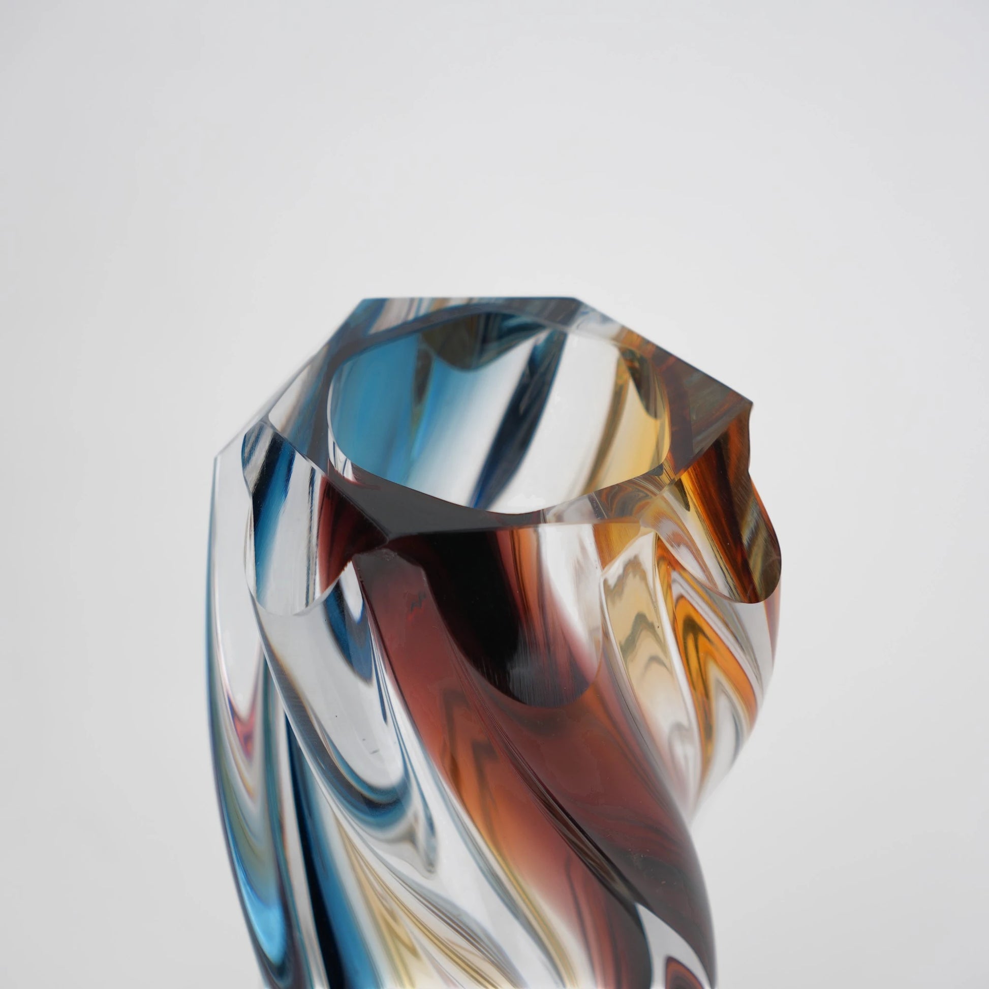 Multicolored twisted sculptural glass vase with elongated form and fluid wave-like contours.