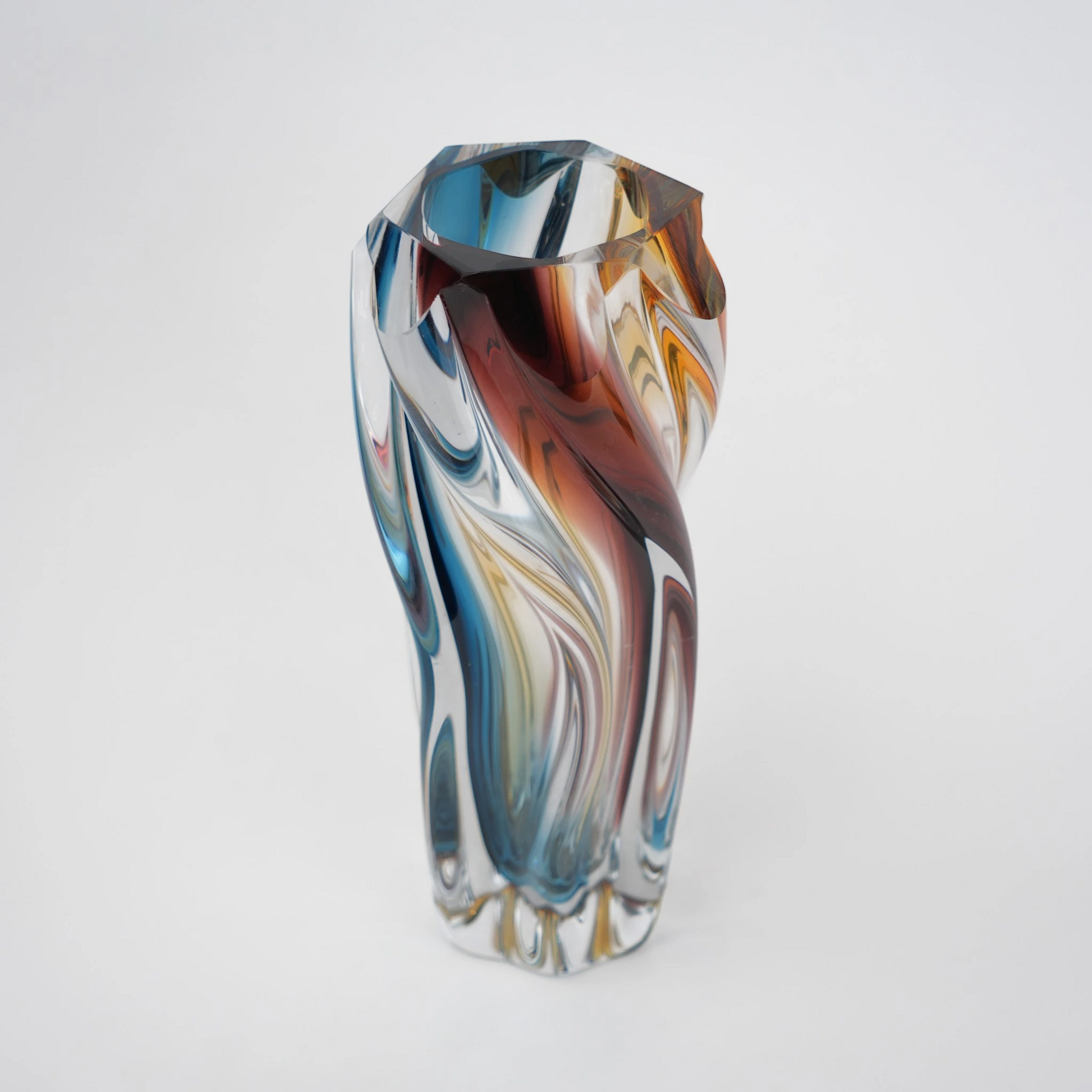 Multicolored twisted sculptural glass vase with elongated form and fluid wave-like contours.